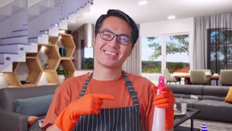 un primer plano de un ama de casa asiático sonriente con un delantal apuntando a un spray mientras está de pie en la casa