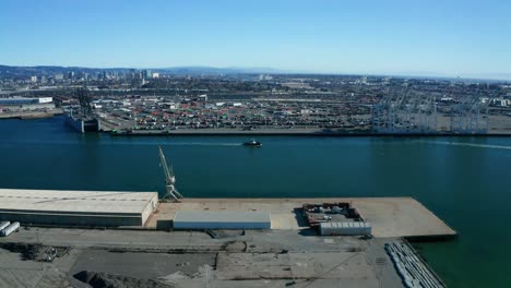 Ein-Kleines-Boot-Vor-Den-Riesigen-Schiffskränen-An-Einem-Sonnigen-Tag-In-Der-Nähe-Der-Stadt-Der-Bucht-Verfolgen