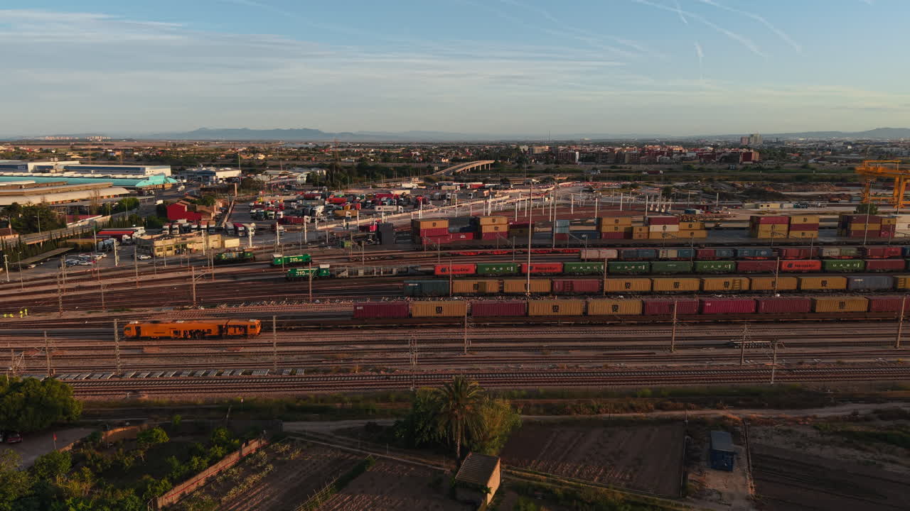Luftaufnahme von einem belebten Güterbahnhof mit Zügen und Schiffscontainern bei Sonnenuntergang