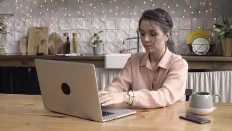 mujer trabajando desde casa en una computadora portátil en la cocina