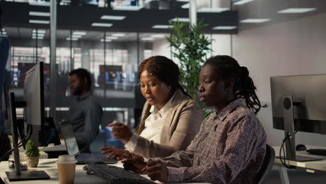 dos mujeres colaborando en el trabajo de computadora por la noche en la oficina