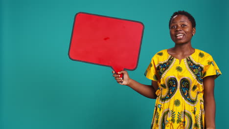 Smiling-person-showing-a-red-isolated-speech-bubble-in-studio