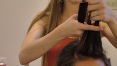 Young-Female-Hairdresser-Backcombs-Woman’s-Long-Brown-Hair,-CLOSEUP