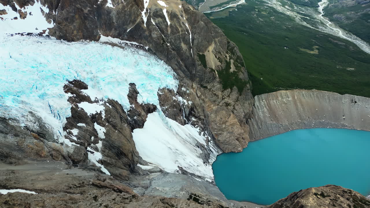 Aerial drone view of a massive glacier descending between rugged mountain slopes, with sweeping views of valleys and distant lakes