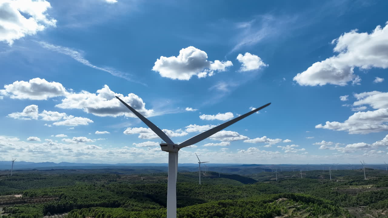 primer plano de las palas de los aerogeneradores girando en el cielo azul con nubes blancas en un día soleado, coll de moro, cataluña en españa