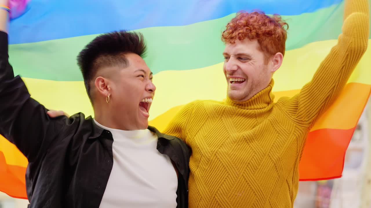 Happy LGBTQ+ couple celebrating with rainbow flag