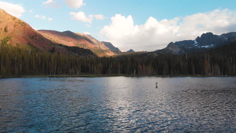 aerial pull back shot of lake with forested shore and glacial mountain view, mammoth california