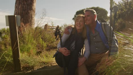 active senior couple sitting on the floor in forest