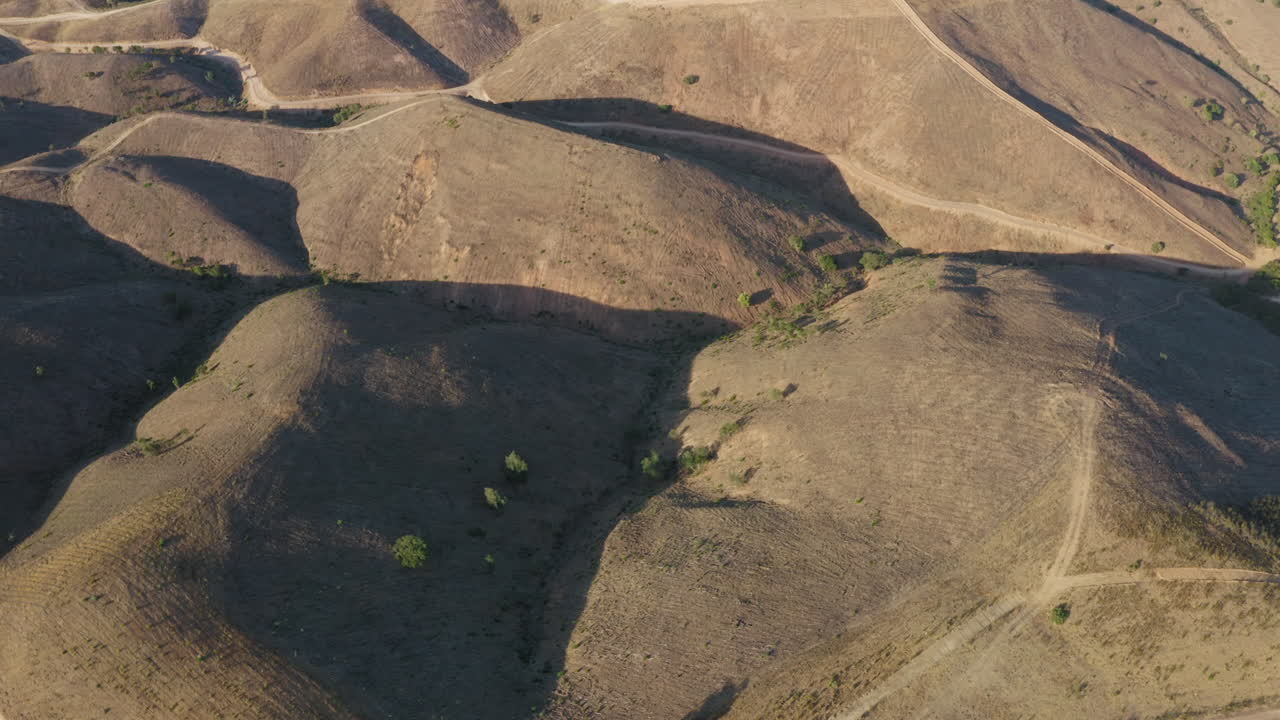 la grúa aérea revela una toma de colinas áridas y secas y senderos de tierra en el algarve, portugal
