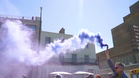 big group of protestants walking by dreamland in margate with purple smoke bombs epic cinematic sun ray beautiful bright sky slow motion