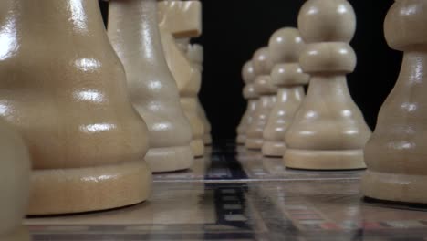 Dolly-macro-shot-of-wooden-chess-figures-lighting-in-front-of-black-background