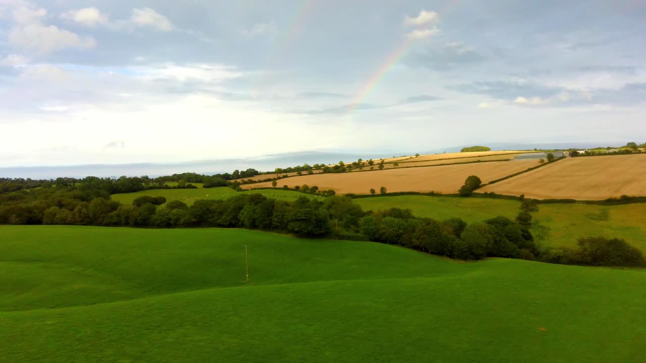vuelo aéreo sobre campo verde con arco iris