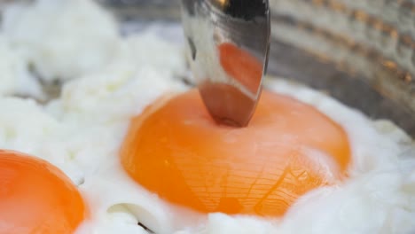 close up of fried eggs with a spoon