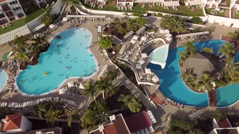 antena de arriba hacia abajo del complejo hotelero con piscina en un paraíso tropical con un día soleado de palmeras