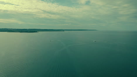 Dos-Lanchas-En-Mar-Claro-Y-Tranquilo,-Toma-Aérea-En-Cámara-Lenta-De-Gran-Horizonte