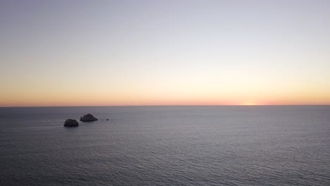 Seascape-Panorama-of-Calm-Ocean-Sea-at-Sunset,-Aerial-Establishing-View-of-Coastline-and-Vast-Water-Surface,-Small-Islands-and-Skyline-in-Horizon