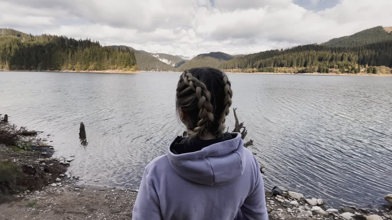 En kvinde set bagfra med flettet hår nær Bolboci-søen i Bucegi-bjergene, Rumænien
