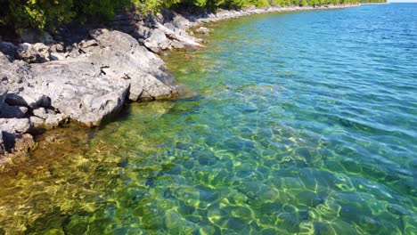 low-flying aerial over crystal clear northern mountain water in a freshwater lake