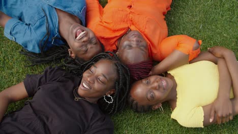 overhead view of cheerful black family lying on grass in circle