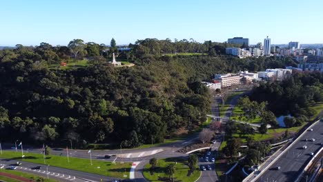 Drone-Aerial-View-of-Kings-Park-with-War-Memorial,-Freeway-and-Row-of-Gum-Trees-on-Fraser-Avenue