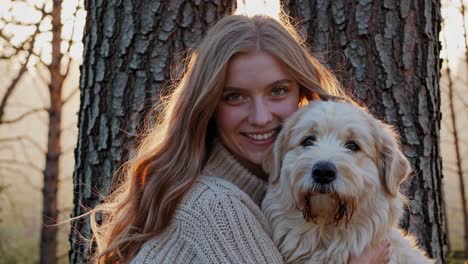 warm sunbeams penetrating woodland foliage, highlighting loving connection between smiling woman hugging soft, furry canine companion amid peaceful forest greenery