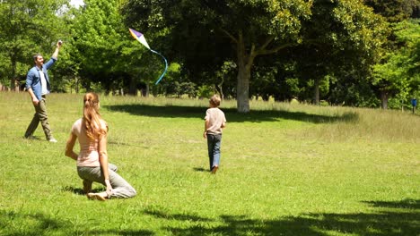 niño pequeño y padres volando una cometa en el parque