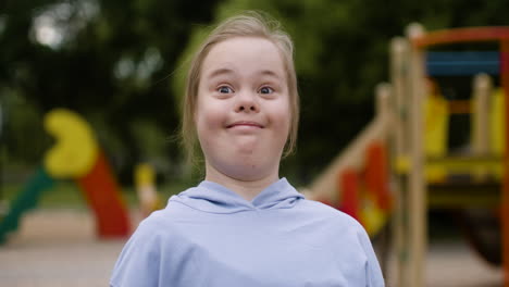 una niña con síndrome de down mirando algo con una expresión asombrada en el parque