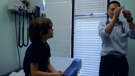 vista frontal de un joven médico masculino asiático preparando una jeringa frente a un niño caucásico paciente 4k
