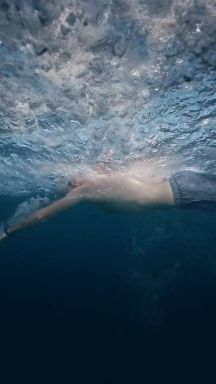 Lone swimmer with a white cap crossing calm open water