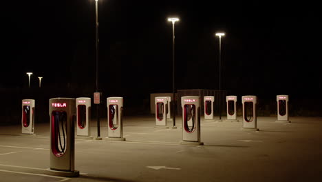 tesla supercharger charging stations illuminated by street lamps at night, zoom