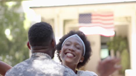 Feliz-Soldado-Afroamericano-Abrazando-A-Su-Esposa-Con-Bandera-Americana,-En-Cámara-Lenta