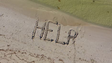 HELP-written-in-the-sand-at-an-angle-and-gets-smaller-as-aerial-camera-rises