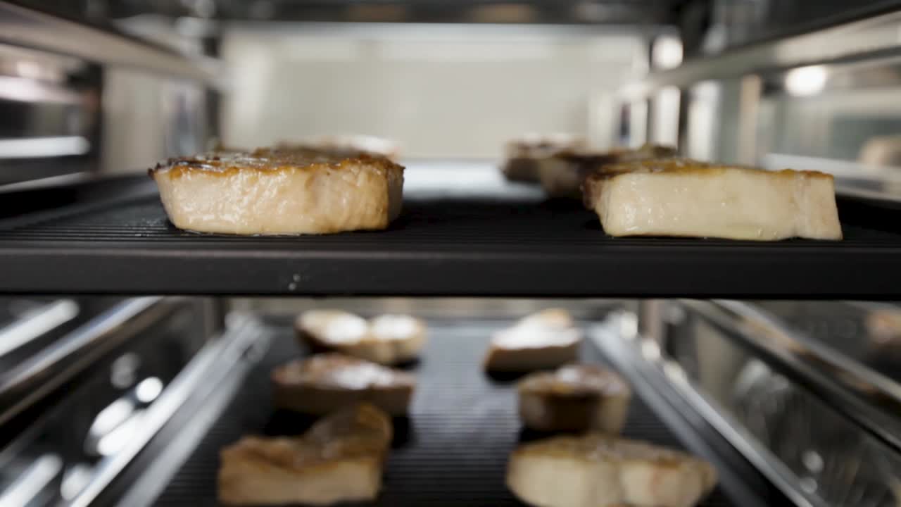 Slices of meat being grilled inside a commercial oven in a kitchen setting, close-up