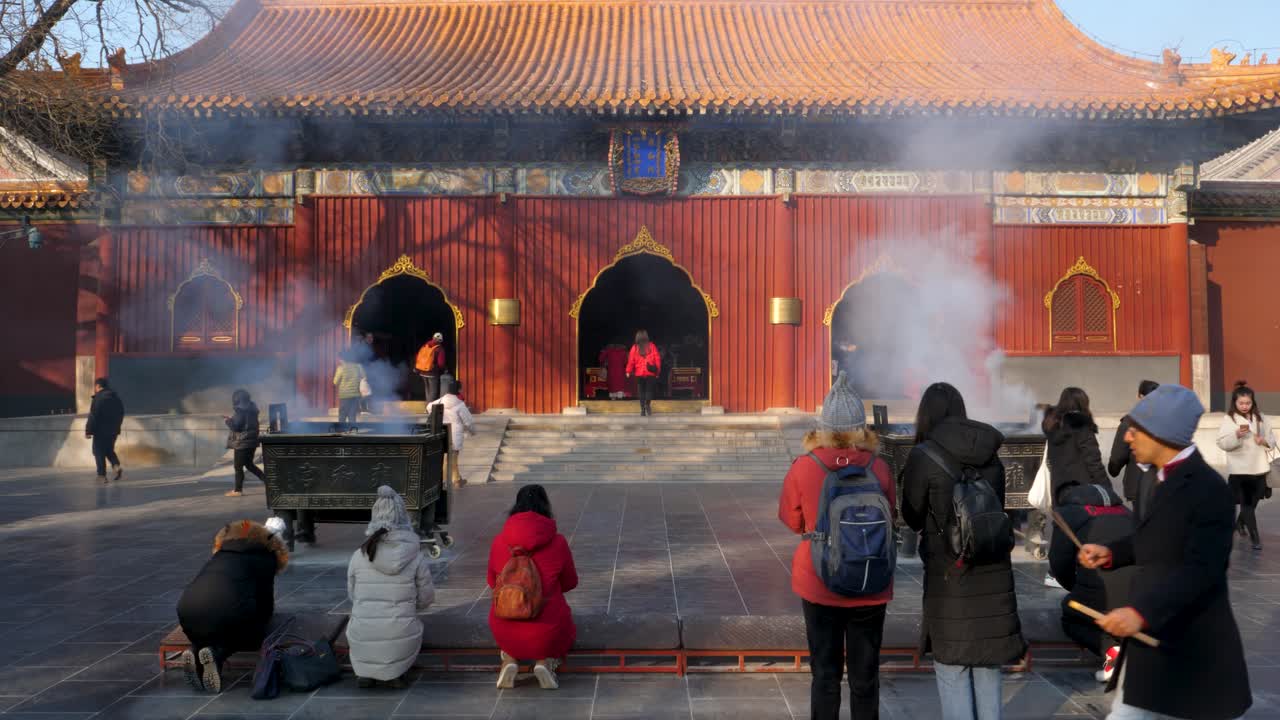 Visitors engage in a serene ritual at the historic Lama temple in Beijing China surrounded by incense smoke during a winter day tripod static shot