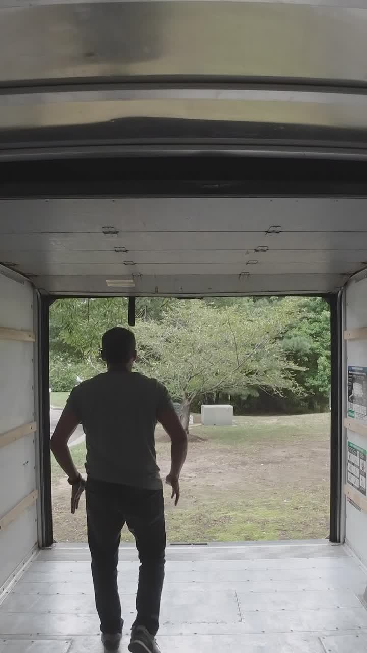 Uomo che chiude il portellone posteriore di un camion in movimento