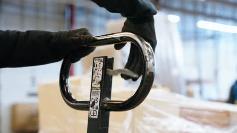 warehouse employee lowers a load using a pallet jack in an industrial setting