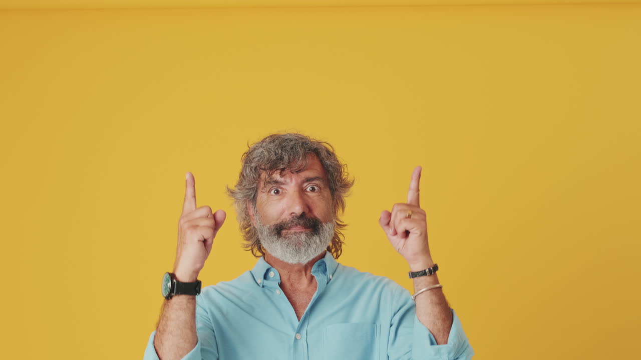 Homem Surpreso Apontando os Dedos para Cima em Fundo Amarelo