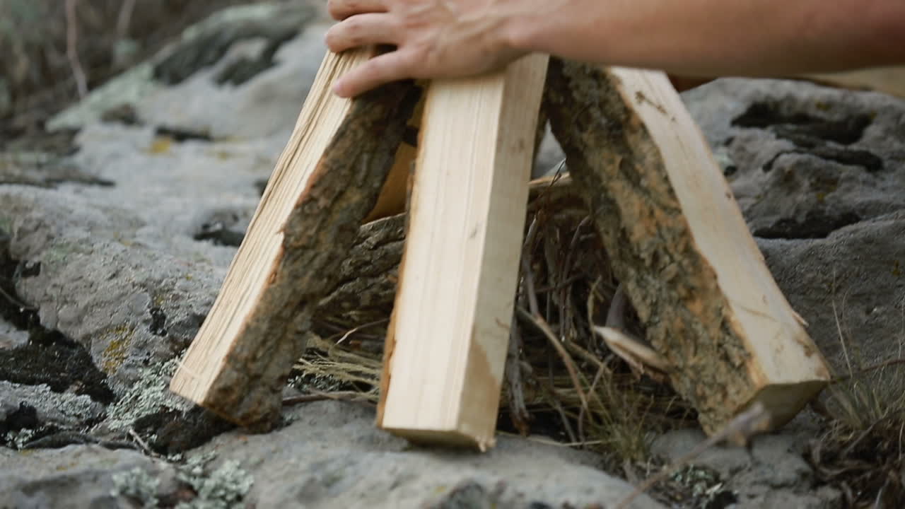 Making Fire In The Forest. Young man kindles a fire in summer wood