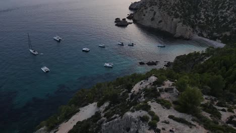 view of descending cliffs and looks sailboats docked in cala d'egos beach, spain