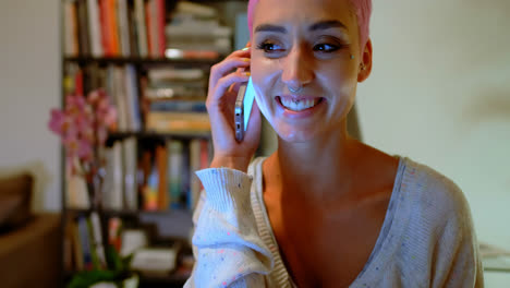mujer de cabello rosa hablando por teléfono móvil en casa 4k