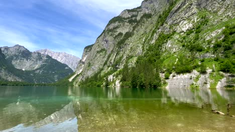 Tilt-down-shot-of-peaceful-mountain-landscape-and-clear-natural-Lake-during-sunny-day-with-blue-sky---Green-plants-growing-on-rocky-wall---Environmental-Conservation-of-Nature