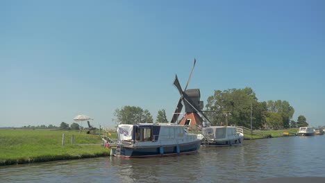 Holländische-Alte-Amerikanische-Windmühle-In-Der-Nähe-Des-Wassers,-Die-In-Zeitlupe-Vorbeisegelt-Und-Sich-Im-Wind-Dreht