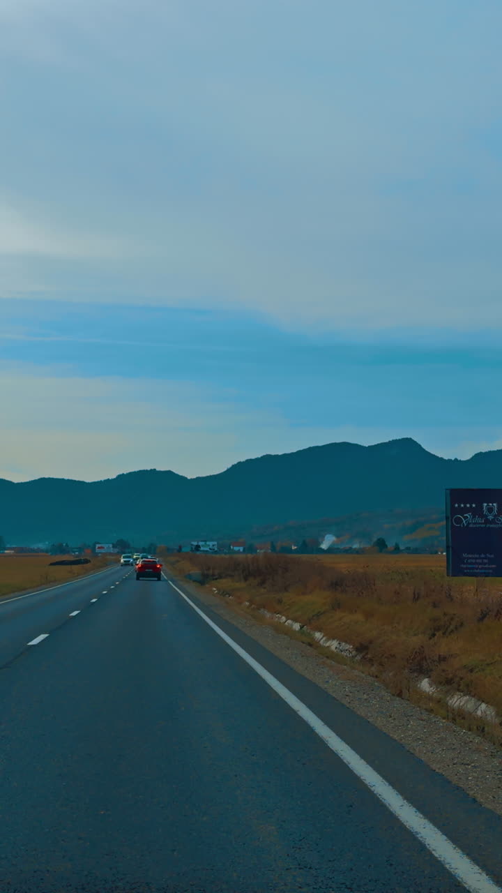 Heading to the mountain range by the highway in valley. Drive by the speedway after sunset. Vertical video