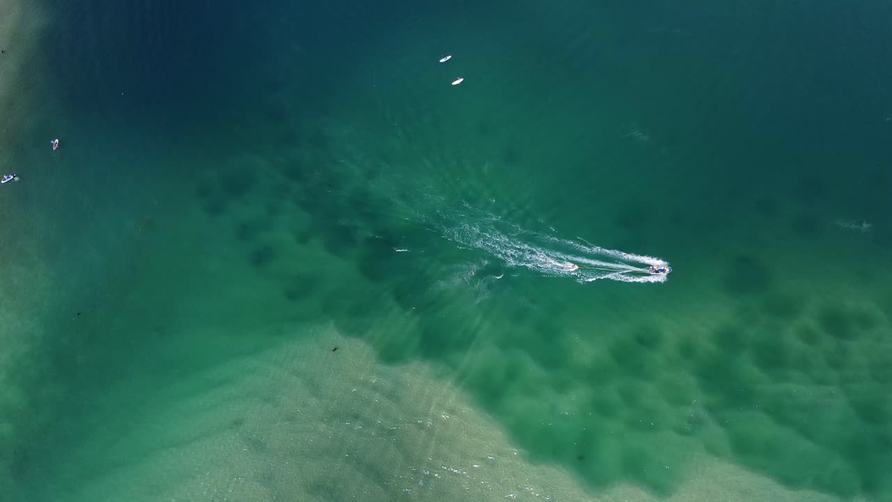 탈레버제라 크릭의 반짝이는 물 위에서 순항하는 쾌속정의 하향식 전망 - 호주 퀸즐랜드 팜 비치의 여름 모험 - 공중 드론