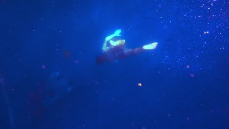 a man freediving deeper and deeper into the blue ocean