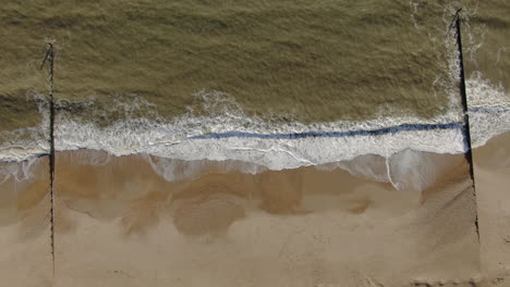 aerial up motion ooking down peaceful golden colored beach from with waves crashing bournemouth uk english channel surf pacific ocean