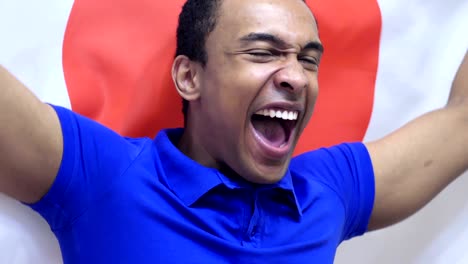 japanese fan celebrating while holding the japanese flag in slow motion