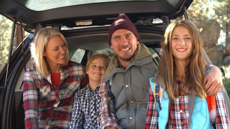 family sitting in open trunk of car, close up handheld shot