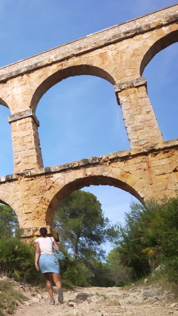 Donna che cammina sotto l'antico acquedotto romano di Tarragona