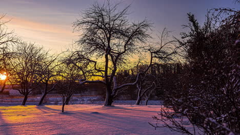 colorful winter sunrise with the golden dawn casting shadows across the snow - time lapse